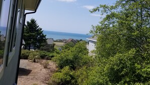 A view from a window overlooking a coastal area with houses, greenery, and the sea. - Great location on a 9 hole, golf course, short walk to the ocean. (Shelter Cove)