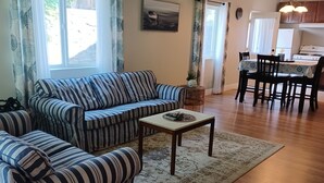 A living room with striped sofas, a coffee table, and a rug. There is a dining area with a table and chairs. - Great location on a 9 hole, golf course, short walk to the ocean. (Shelter Cove)