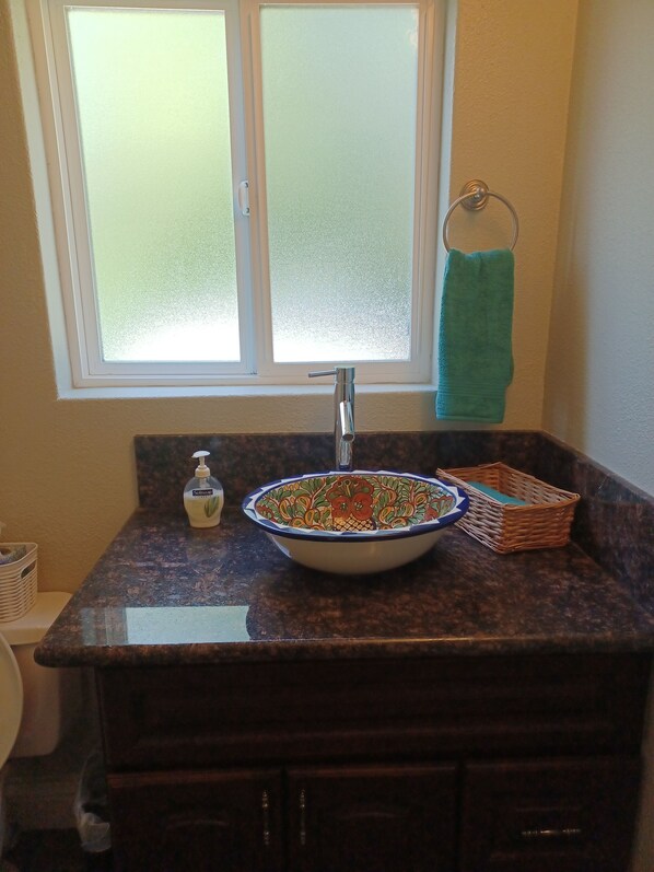 A bathroom with a sink, faucet, and window.