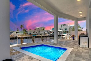 Una piscina con vistas a un puerto deportivo y edificios al fondo.