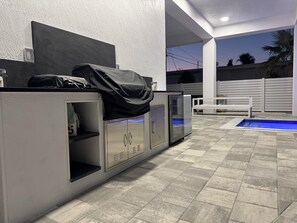 An outdoor pool area with a built-in grill and storage cabinets. - Catch n' Relax Anglers Ultimate Waterfront Retreat with 50’ Dock Modern New Home (Marathon)