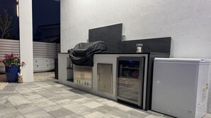 A modern outdoor kitchen area with a built-in refrigerator, a sink, and a cabinet.