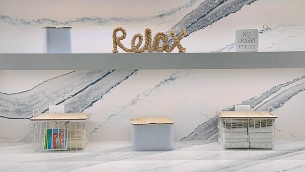 A laundry area with two washing machines, a cabinet, and a shelf with a 'Relax' sign and a 'No Crabby Attitudes' sign.