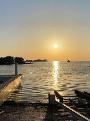 A sunset over a calm body of water with a dock and a bench. - Catch n' Relax Anglers Ultimate Waterfront Retreat with 50’ Dock Modern New Home (Marathon)