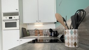 Una cocina moderna con armarios blancos, encimera de madera, cafetera y una pared decorada con un corazón.