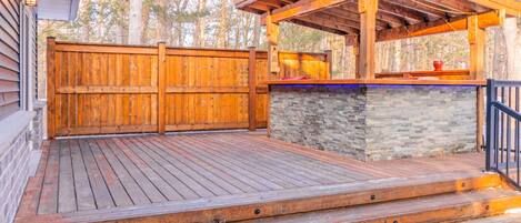 A wooden deck with a stone wall and a covered seating area.
