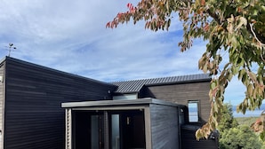 Une maison moderne dotée d’un garage, d’un porche et offrant une vue sur le paysage environnant.