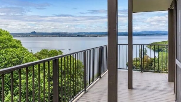 Un balcon avec vue sur un lac et des montagnes lointaines.