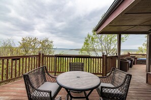 A wooden deck with wicker furniture and a view of a lake.