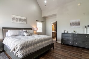 A bedroom with a bed, dresser, and artwork on the walls.