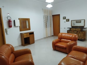 A living room with two leather sofas, a small wooden cabinet, a fire extinguisher, and a mirror on the wall. - LOCAZIONE TUR. GAMBINO MARIANA NICOLETTA (Agrigento)