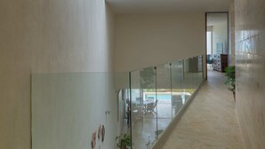 A modern interior with a glass railing, a tiled floor, and a staircase with skylights. - Casa Almeja - Yucatan Home Rentals (Chicxulub)