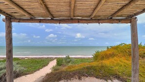 A beach view under a wooden pergola with a clear sky. - Casa Almeja - Yucatan Home Rentals (Chicxulub)