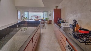 A modern kitchen with a central island, a dining area with a view, and a kitchen counter with appliances. - Casa Almeja - Yucatan Home Rentals (Chicxulub)