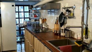 A kitchen with a wooden countertop, stainless steel sink, and various kitchen utensils.