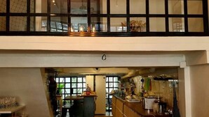 A spacious interior with a high ceiling, a kitchen area with bar stools, and a dining area with a long table and chairs.
