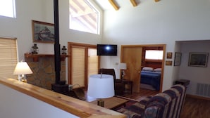 Un interior acogedor con chimenea de piedra, televisor, sofá y techo de madera.