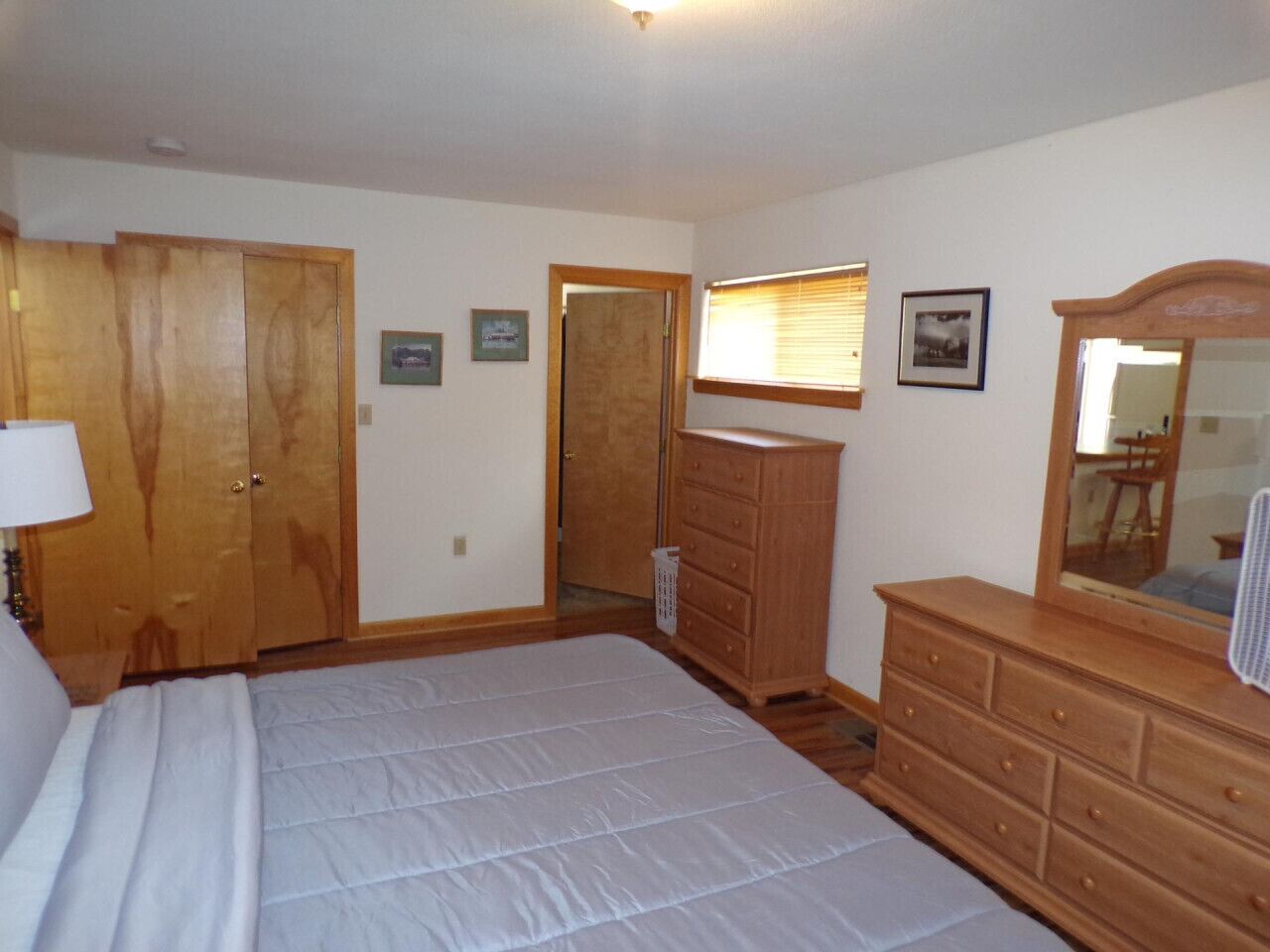 Un dormitorio con una cama grande, armario de madera, cómoda y un espejo.