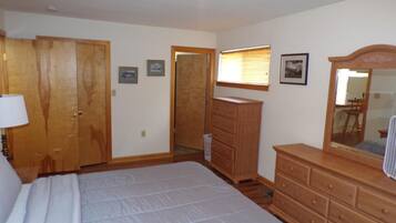 Un dormitorio con una cama grande, armario de madera, cómoda y un espejo.