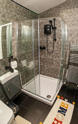 A modern bathroom with a glass-enclosed shower, a sink with a towel rack, and a toilet.