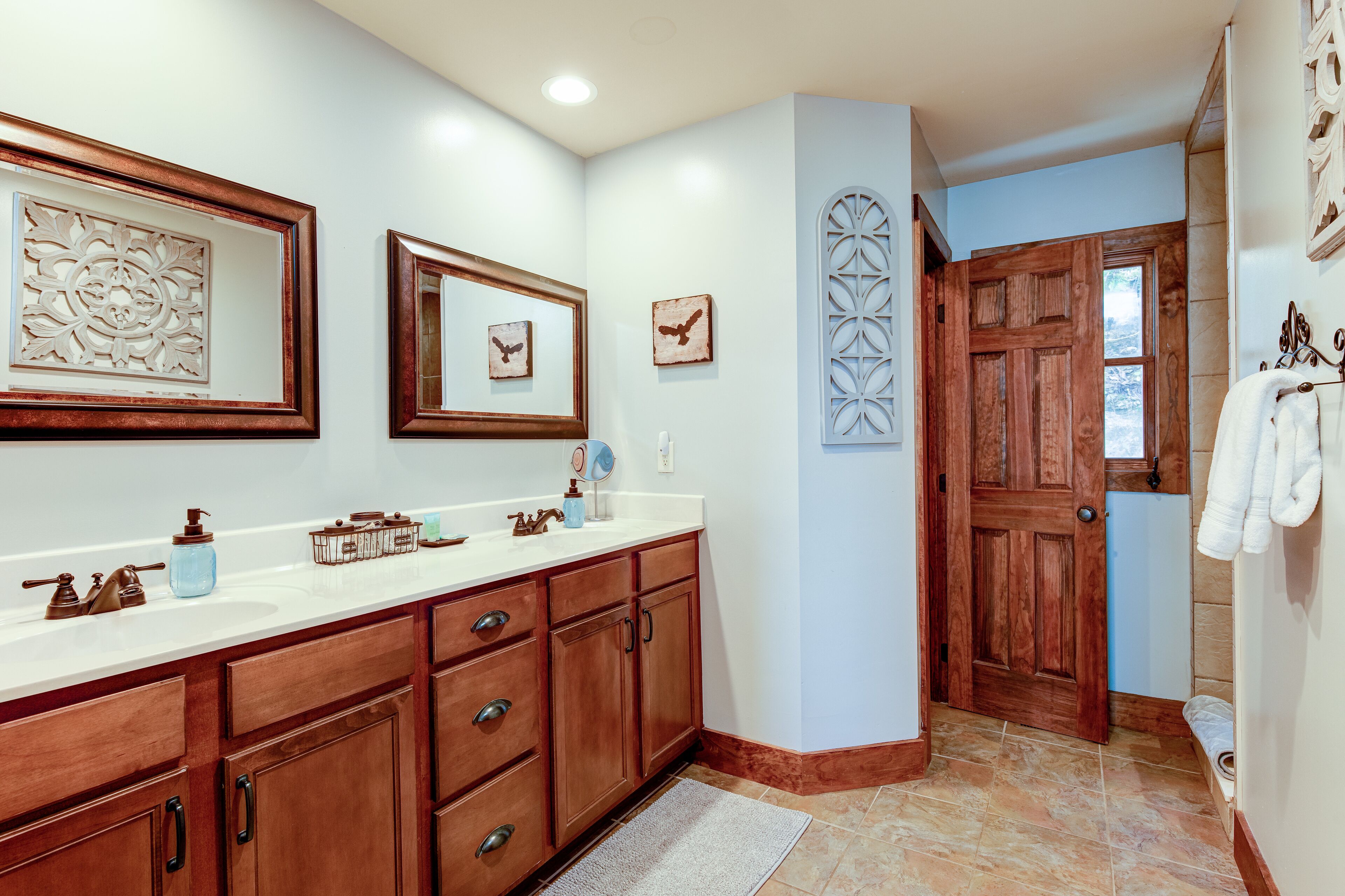 Un baño con armarios de madera, un lavabo blanco y una puerta de madera.