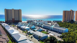 A coastal hotel with multiple buildings, a parking lot, and a view of the ocean.