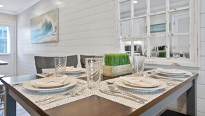 A dining table set with plates, glasses, and cutlery, with a decorative centerpiece and a painting on the wall.