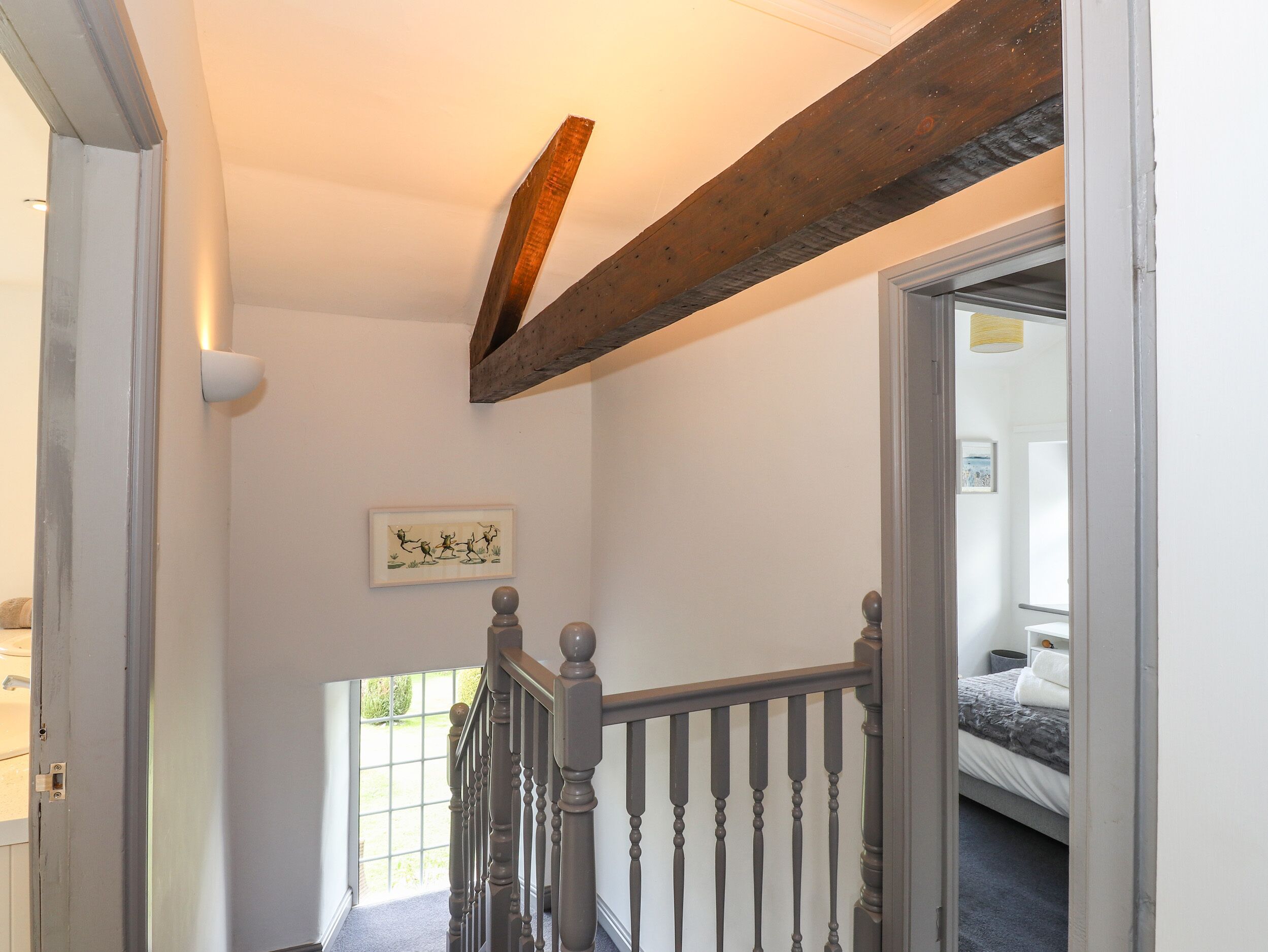 A staircase with wooden balusters and a dark wooden beam above.