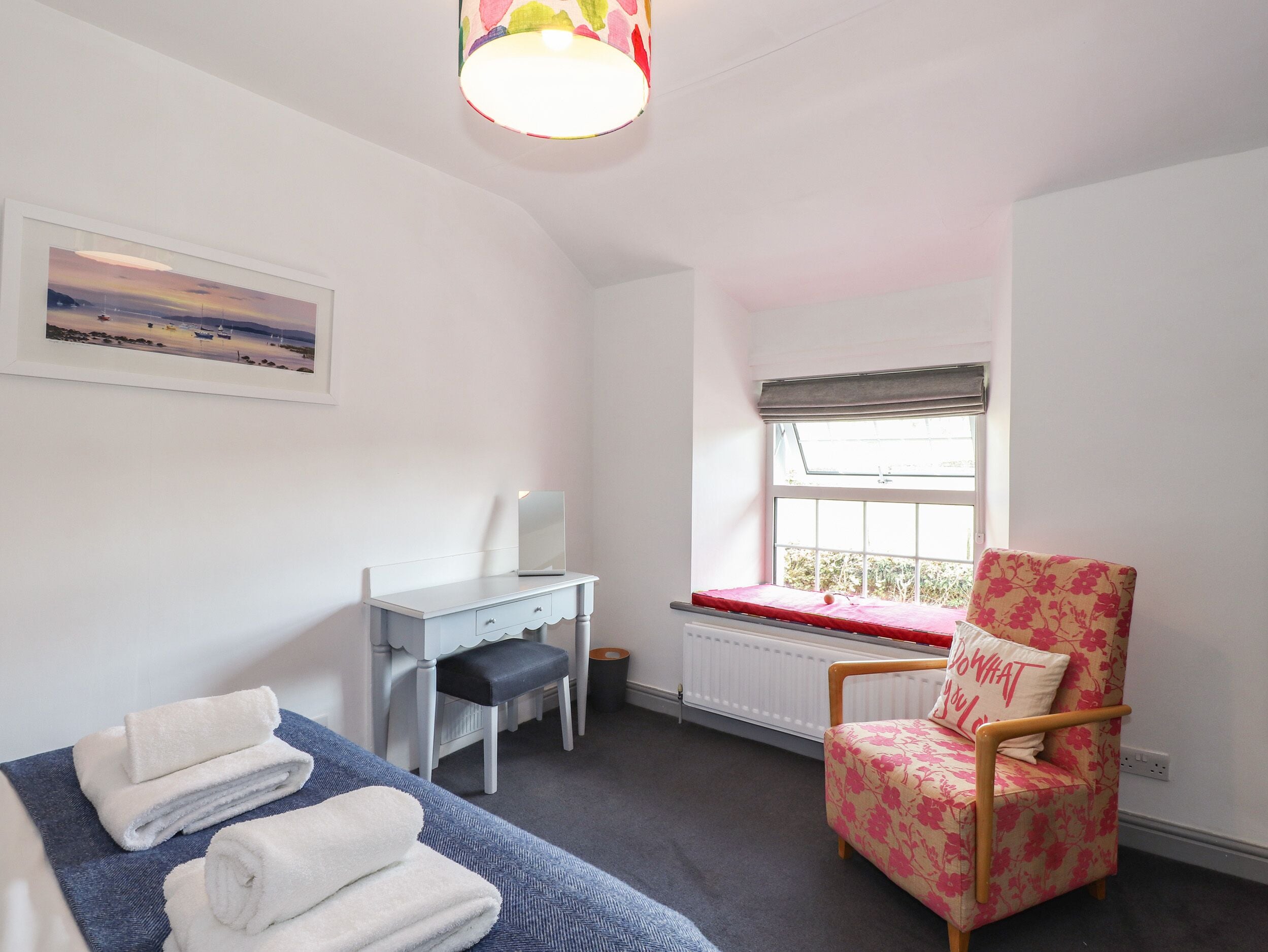 A bedroom with a bed, a desk, a chair, a window, and a radiator.