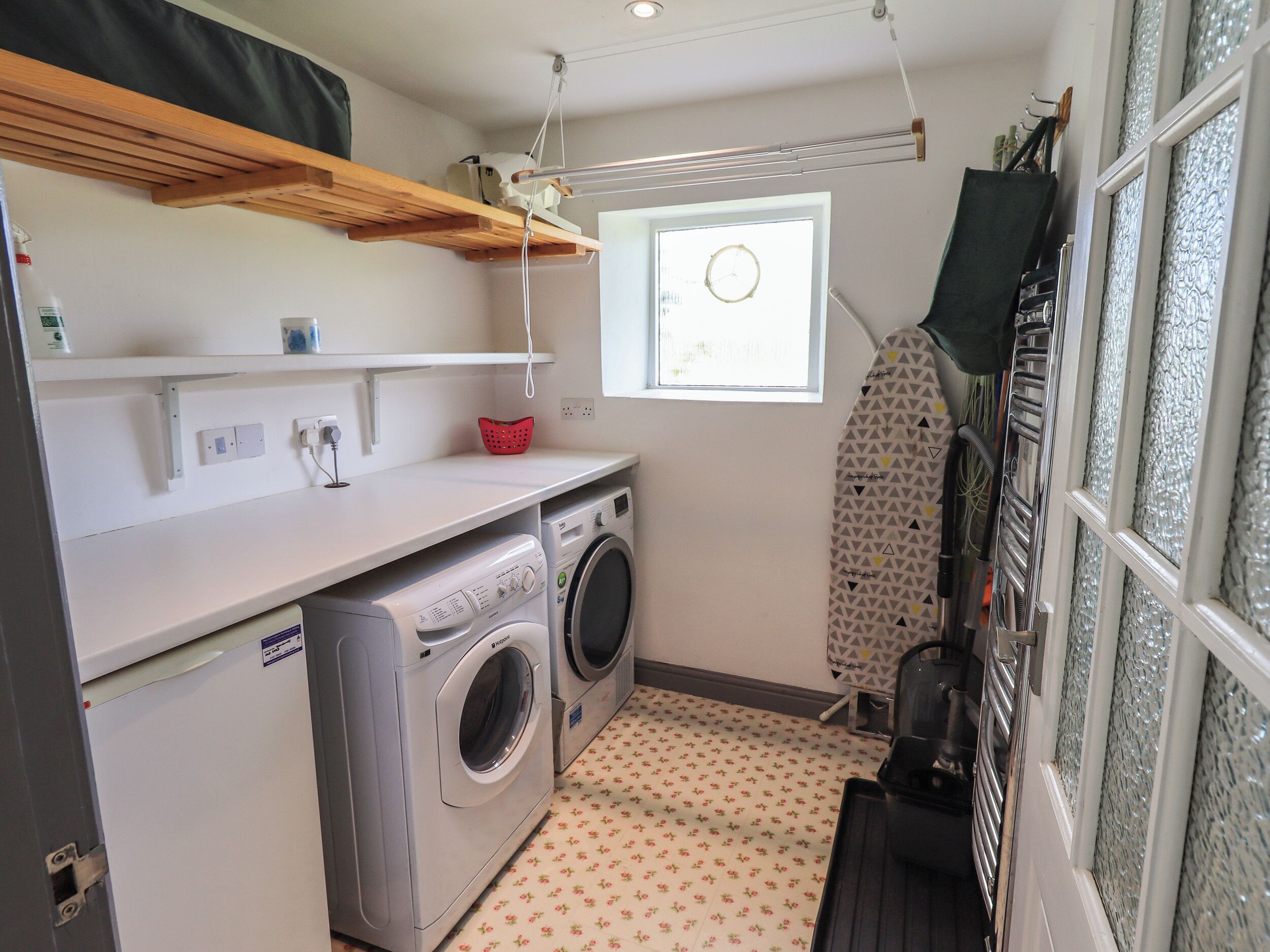A compact laundry room with a washing machine, dryer, and ironing board.