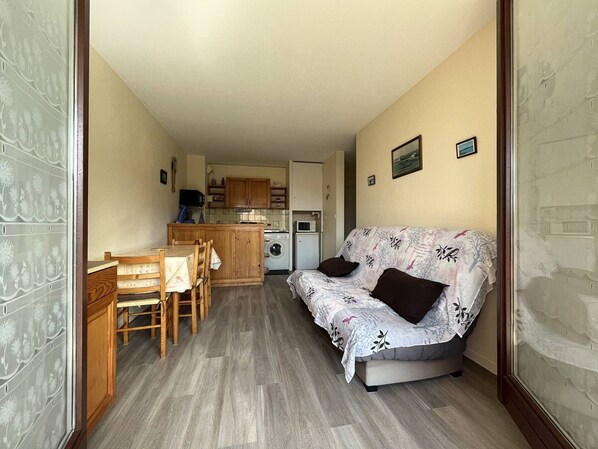 A compact living space with a kitchenette, a sofa, a dining table, and chairs.