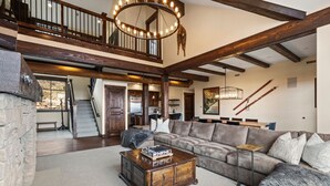 A spacious living room with a large sectional sofa, a wooden coffee table, and a staircase leading to an upper level.