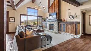 A spacious living area with a stone fireplace, a large sofa, and a view of the outdoors.