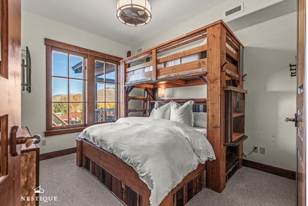 A bedroom with a bunk bed, a large window, and a view of the outside.