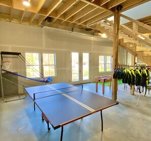 An indoor recreational area with a foosball table, a ping pong table, and a basketball hoop. - New! Beautiful Lakefront Home near Burlington, VT (Hinesburg)