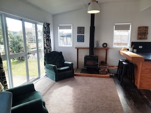Un salon chaleureux avec une cheminée, un fauteuil confortable et un coin bar.