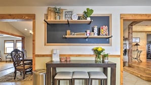 A kitchen with wooden beams, a coffee station, and a bar area with stools.