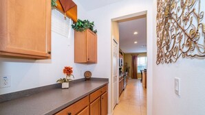 Una cocina con armarios de madera, una encimera, una planta en maceta y un adorno en la pared.