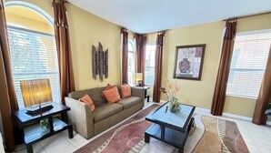 Una sala de estar con sofá, mesa de centro y mueble para televisión.