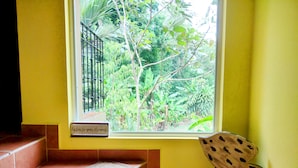 Ein Zimmer mit Fensterblick auf einen Garten, einer Bank und einem Schild mit dem Aufschrift 'hör deinen Träumen zu'.