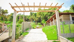 Ein Weg führt zu einem Haus mit einer hölzernen Pergola darüber.