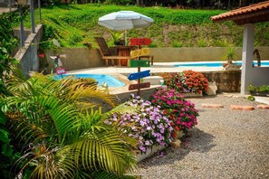 Ein Poolbereich mit einem Wegweiser, Gartenmöbeln und verschiedenen Pflanzen.