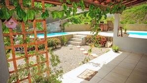 Ein überdachter Patio-Bereich mit Pool, umgeben von Pflanzen und einem Holzbalkon.