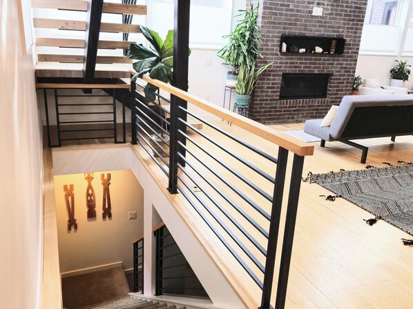 A modern interior with a wooden staircase, a fireplace, and a seating area.