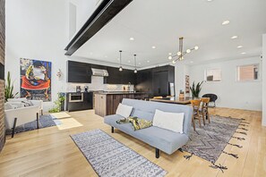 Un espacio de estar moderno con sofá, comedor, cocina y obras de arte.