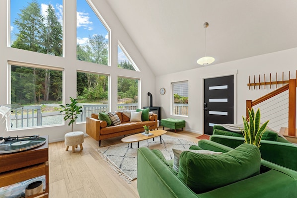 A spacious living room with a large window, a sofa, a coffee table, and a staircase.