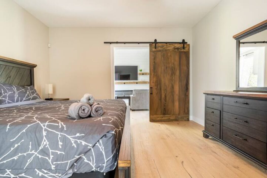 A bedroom with a bed, a wooden wardrobe, a sliding door, and a television in the background.