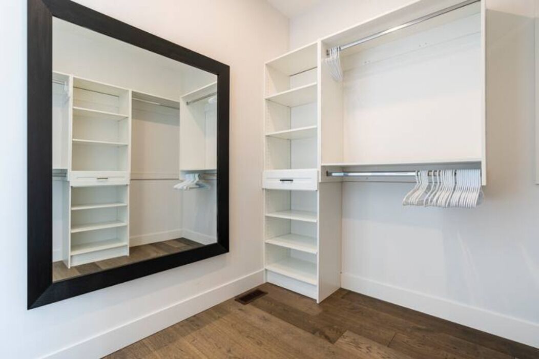 A walk-in closet with open shelving and a mirrored closet door.
