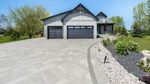 A modern two-story house with a garage, a driveway, and a landscaped garden. - Laporte Cottage | Hot Tub | Walk to Beach | Fire Pit | Grand Bend & Bayfield (Zurich)