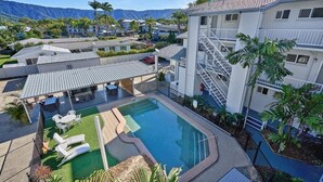 A hotel with a swimming pool, outdoor seating, and a staircase leading to the upper floors. - Cocos Holiday Apartments (Trinity Beach)